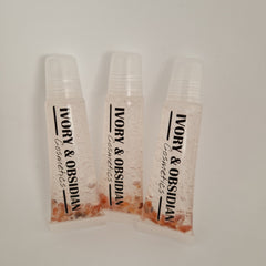 Lip gloss tubes with clear plastic, pink liquid, and Ivory & Obsidian Cosmetics text