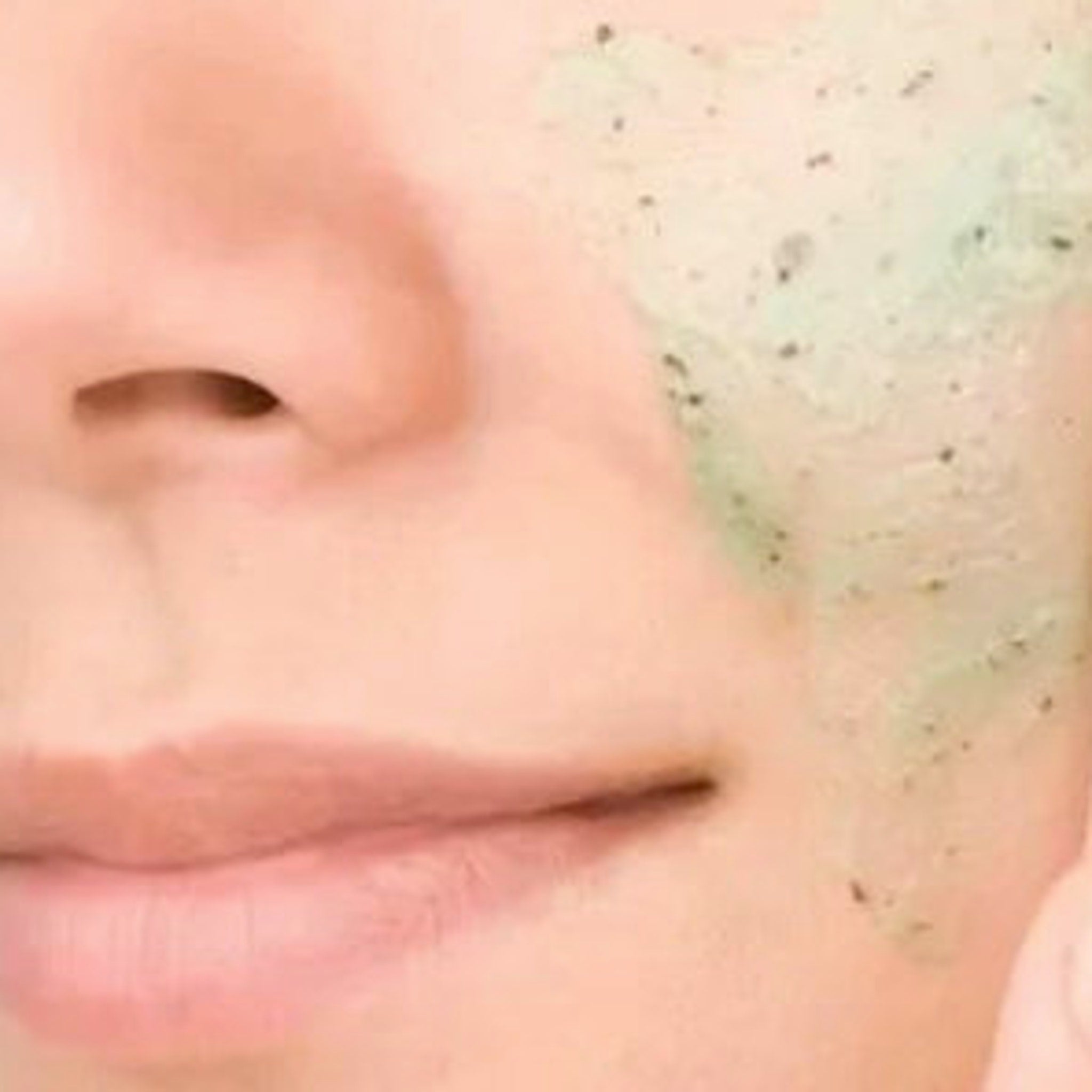 Facial Cleanser with green and black scrub applied to face, close-up view