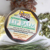Lip balm tin with Desert Rose label, silver metal, surrounded by herbs