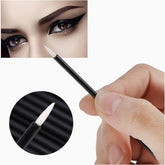 Flat lay of 50 white disposable eyeliner brushes with fine pointed tips in clear plastic packaging