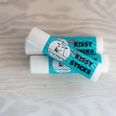 Lip balm tubes, white and teal, with "Kissy Sticks" text and Goat Fetching Soap logo on each tube