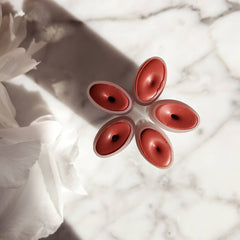 Lip & cheek stain product in red oval containers on marble surface with white flower