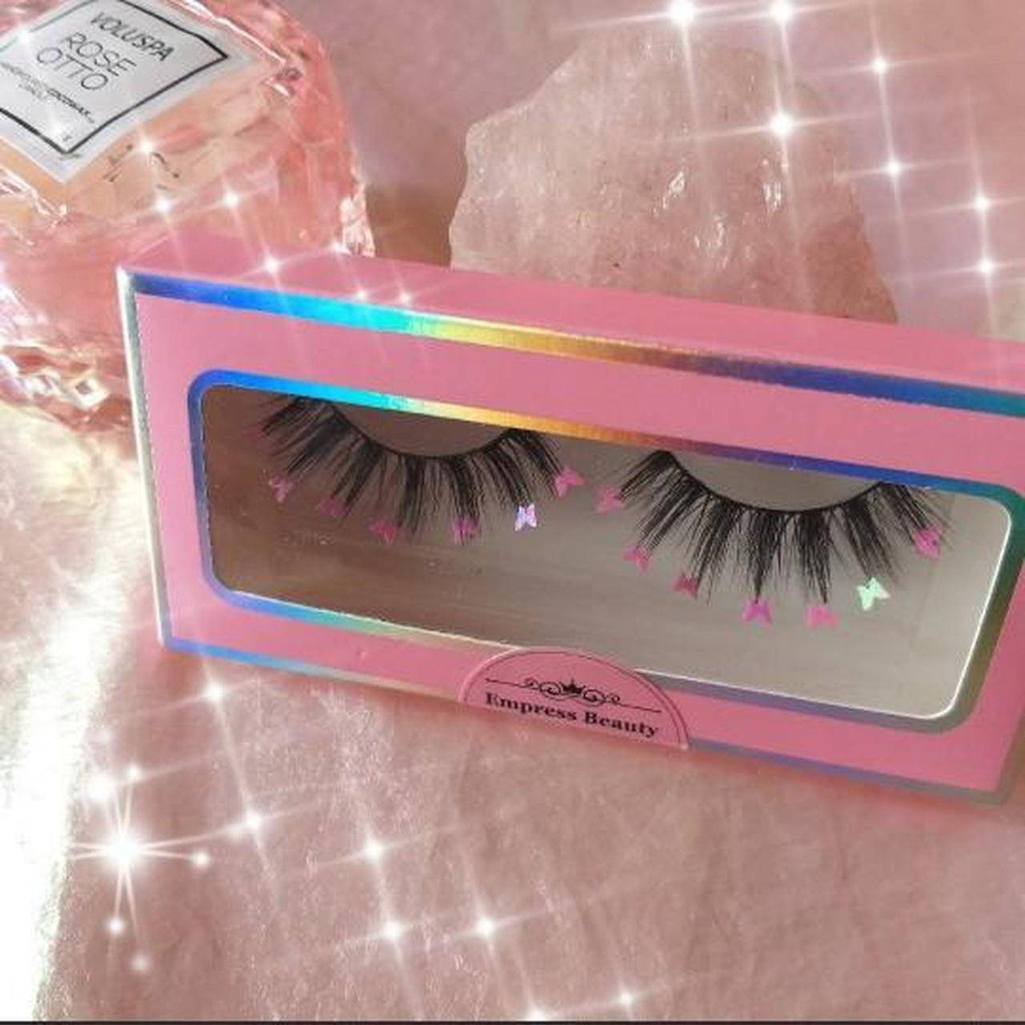 False eyelashes with black lashes, pink butterfly accents, and Empress Beauty branding on box