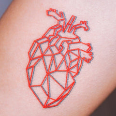 Close-up of skin-friendly red geometric heart tattoo with glossy finish, adhering smoothly to bare skin