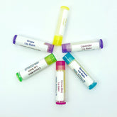 Lip balm tubes in various colors with labels, arranged in a circle, Nanas Naturals brand visible