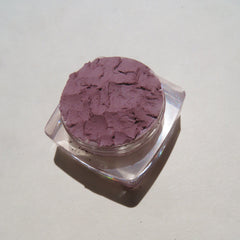 Eyeshadow compact with purple powder, clear plastic container, and shadow on white background