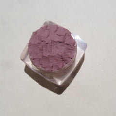 Side view of matte purple loose mineral eyeshadow in a clear sifter jar, showcasing fine powder texture.
