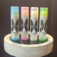 Lip balm tubes with assorted color tops and "cobun" text, on a white tray