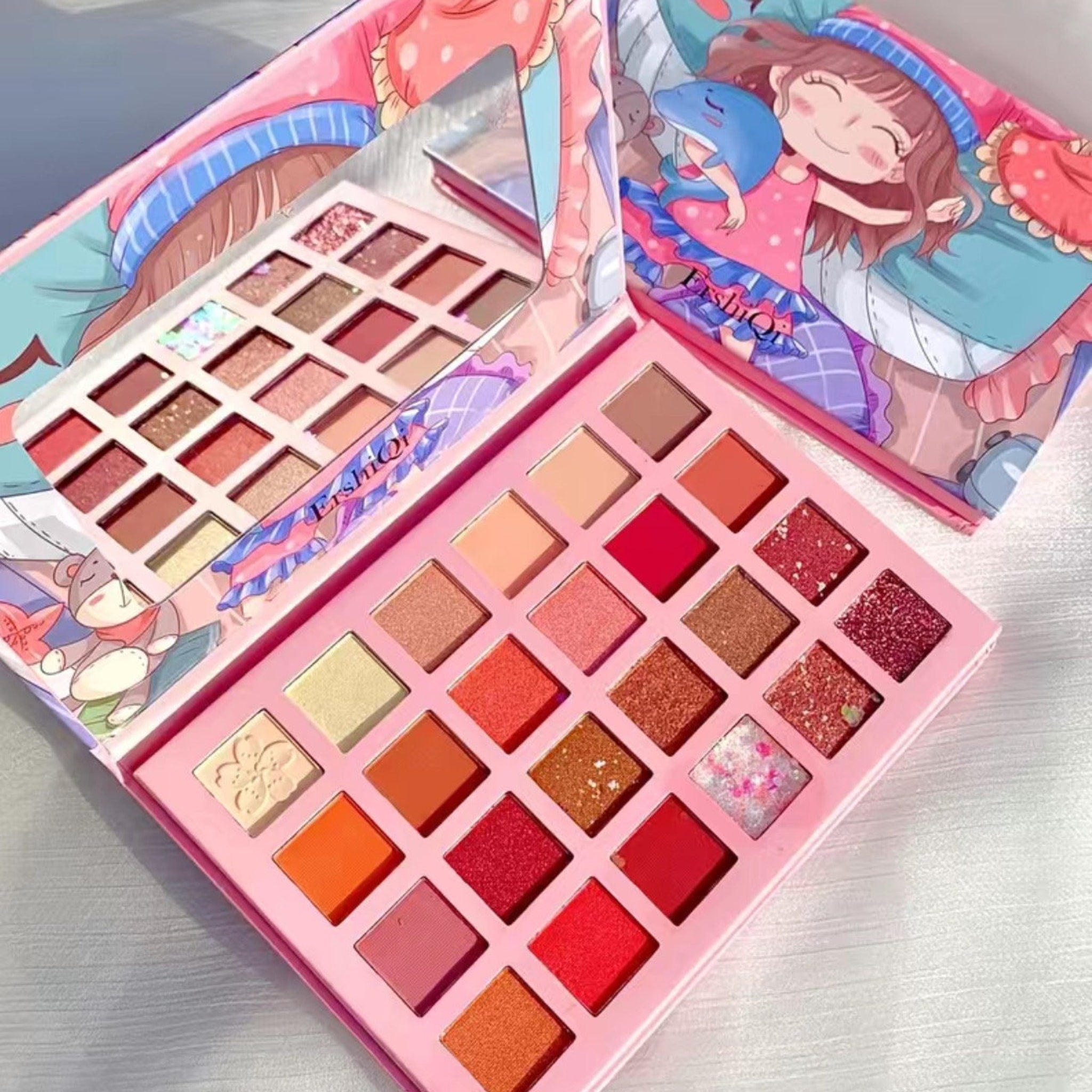 Colorful 24-pan eyeshadow palette with matte and glitter shades in a playful cartoon-themed compact.