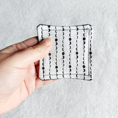 Square fabric pad with white and black moon phase pattern, held in hand