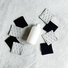 Makeup remover pads, black and white fabric with moon pattern, with white bottle on white towel