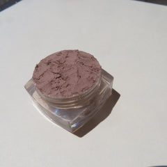Side view of matte brown loose mineral eyeshadow in eco-friendly packaging with mica shimmer particles visible
