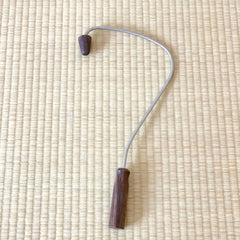 Neck massager tool with dark wood handle and head, silver metal arm, on woven mat