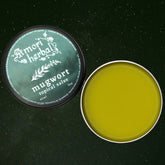 Skin care mugwort salve, green and silver metal tin, Amori Herbals product open on surface