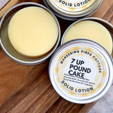 Solid lotion bars in silver tins, pale yellow, round shape, Wandering Pines Cottage brand visible