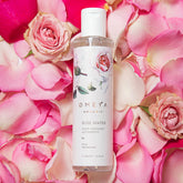 Rose water bottle with white label, surrounded by pink rose petals, OMEYA brand visible