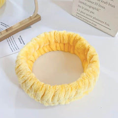 Yellow plush headband with gathered style, used for skincare or beauty routines