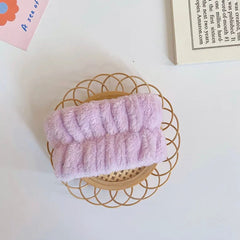 Headband, light purple fluffy material, on a woven circular tray