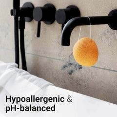 Side view of soft pink konjac sponge with textured surface, resting on bamboo tray with water droplets