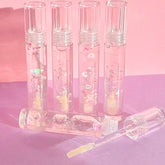 Lip gloss with clear tubes, pink liquid, and heart-shaped glitter, "Heart Strings" text visible
