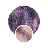 Eyeshadow swatch with glittery purple, brown, and pink shimmer, with skin tone sample