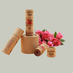 Lip balm tubes in brown cardboard with floral pattern and "innocent lips" text, next to roses