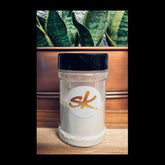 Facial cleanser jar with black lid, white powder, and SkinKona logo on label