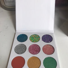 Eyeshadow palette with multiple colors of glitter and matte finish in a white case