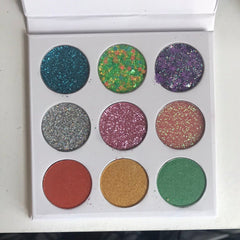Eyeshadow palette with multiple colors, glitter, and round pans in a white case