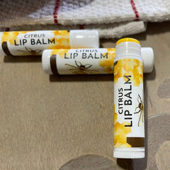 Citrus lip balm tubes with white, brown, and yellow labels, bee design, and text visible