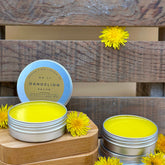 Salves with yellow color in metal tins, on wooden surface, Rooted N Red branding visible