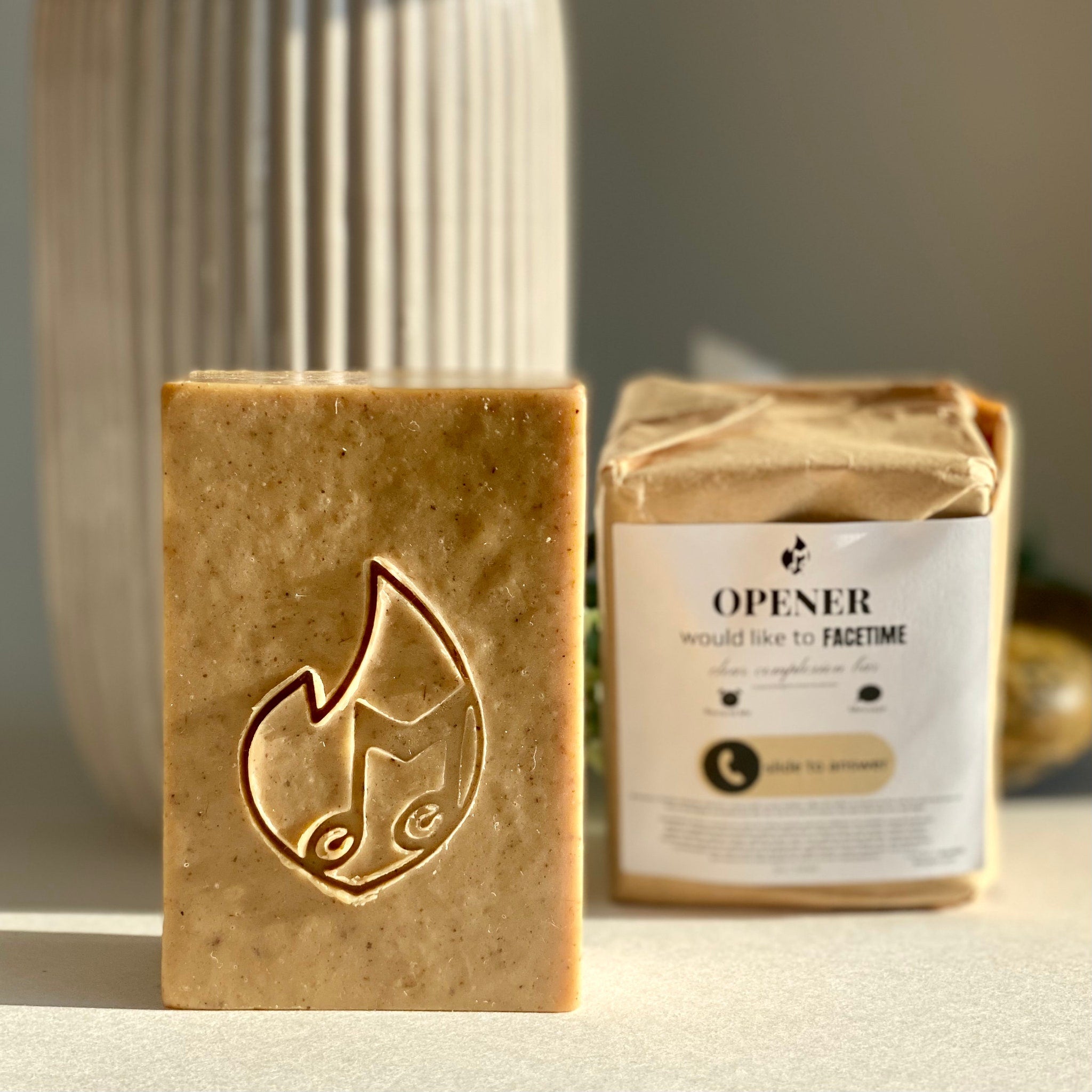 Facial cleanser bar with embossed design, beige color, and OPENER branding on packaging