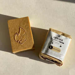 Soap bar with logo, brown color, packaged with "OPENER" label, on white surface