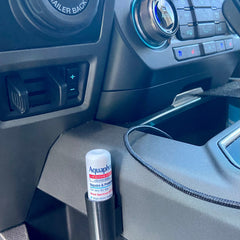Lip balm tube with white and red label, black holder, and car interior background