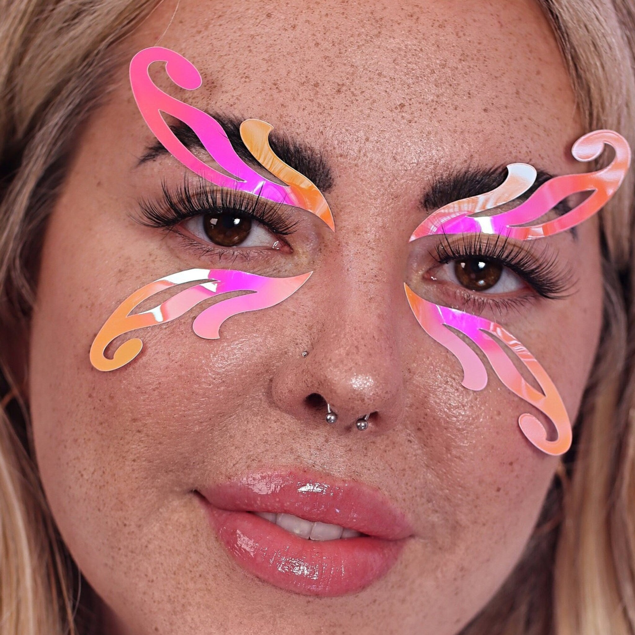 Face makeup face stickers with iridescent peach and pink colors applied to face