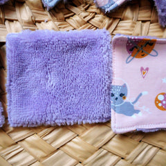 Reusable face pads, purple microfiber, pink patterned fabric, on woven surface