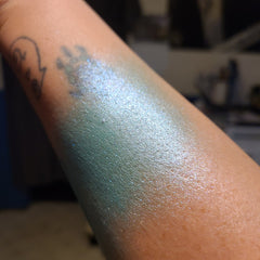Side view of Under Da Sea Super Brite Duochrome Eyeshadow pot showing iridescent color shift from teal to purple