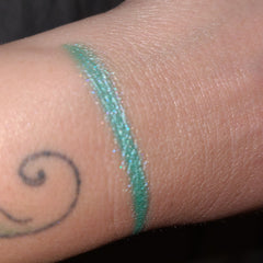 Side view of Under Da Sea Super Brite Duochrome Eyeshadow pot showing color shift from teal to purple
