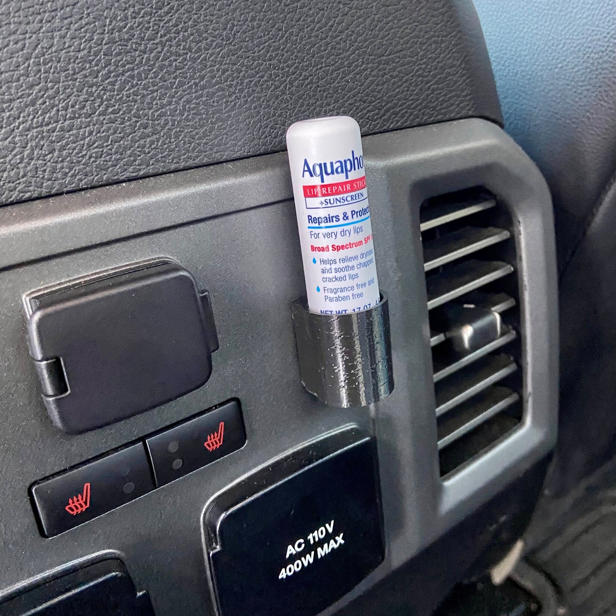 Lip balm holder 3D printed black plastic, holding Aquaphor lip balm in car