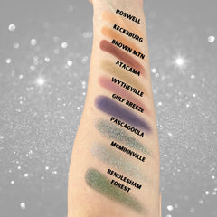 Eyeshadow swatches in various colors on arm, with text labels in black font