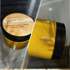 Golden turmeric scrub in a sleek glass jar with wooden scoop on marble surface