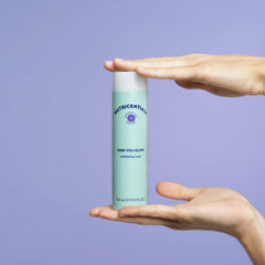 Exfoliating toner bottle, mint green and white, held in hands, with brand name visible