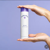 Facial cleanser bottle, white and purple, held by hands, Nutricentials brand visible