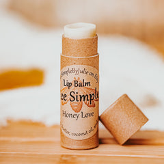 Lip balm in brown paper tube with white balm, "bee Simple" label, and open cap on wood surface