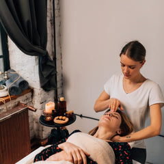 Massage therapy session with woman wearing floral top and white towel, receiving head massage