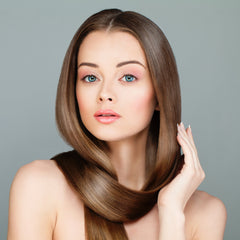 Long brown hair styled sleek, with hand touching, against a grey background.