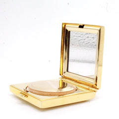 Compact powder in gold metal case with mirror and Estee Lauder text visible