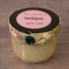 Eucalyptus sugar scrub jar with floral ribbon, black lid, and teal jewel accent.