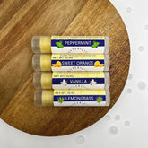 Lip balms, four tubes with clear caps, yellow balm, and Bettericity labels on wood surface