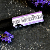 Lip balm tube with purple label, black tube, and lavender flowers on dark surface